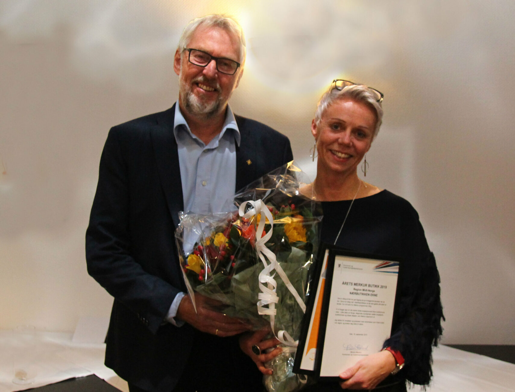 2 personar med blomst og diplom. Foto.