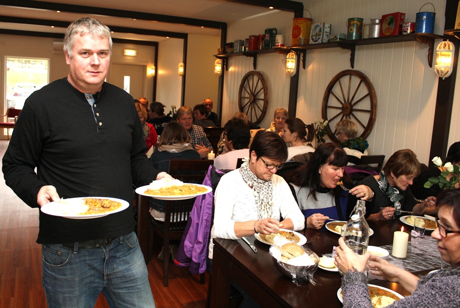 Person med mat på tallerkar i kafé. Foto.