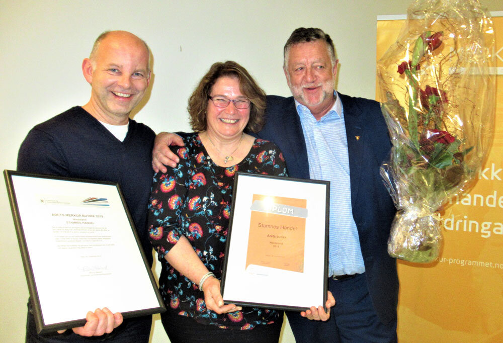 Tre personer med blomster og diplom. Foto.