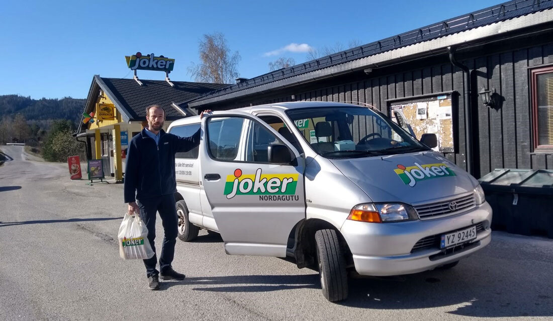 En person med handlepose står ved en bil