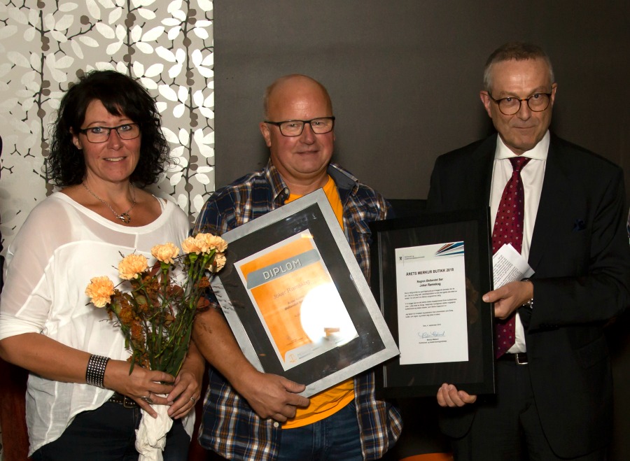 3 personar med blomst og diplom. Foto.