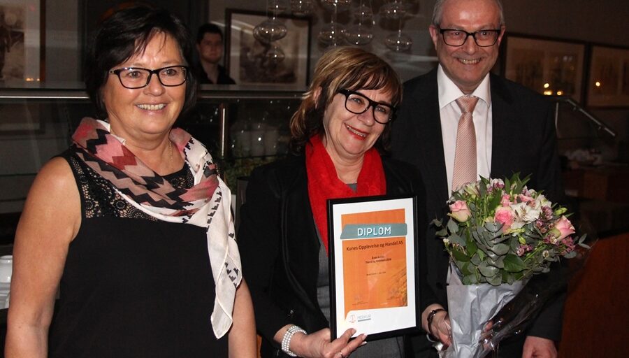 3 personer med blomst og diplom. Foto.