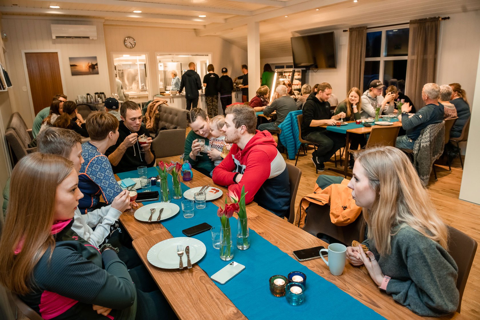 Mange personer samlet rundt flere langbord. Foto.