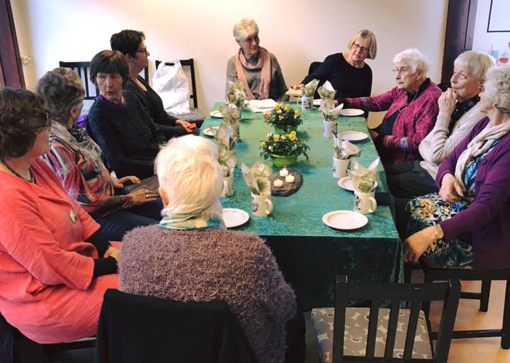 Mange eldre personer samlet rundt et bord. Foto.