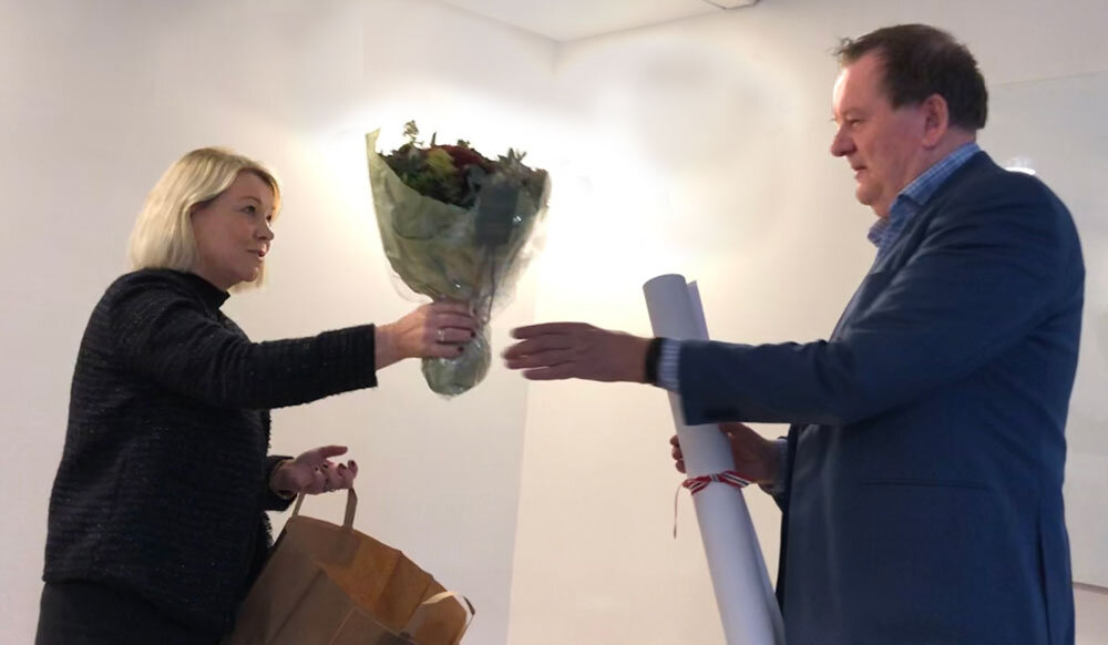 Blomsteroverrekkelse mellom to personer. Foto.