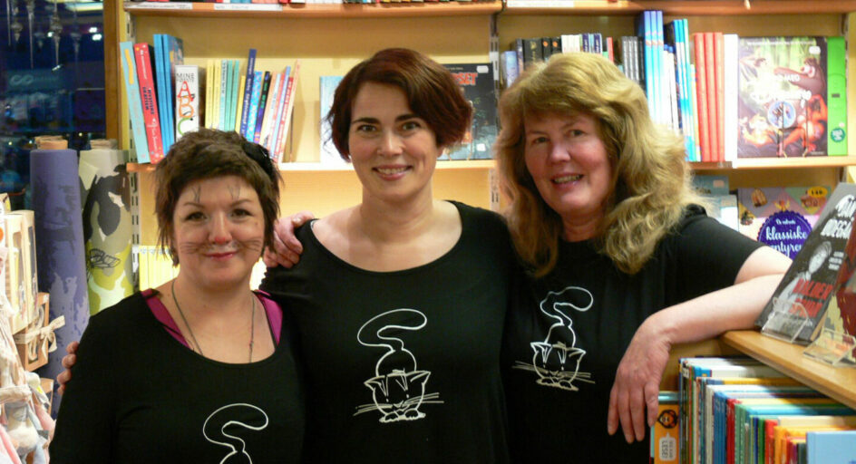 3 personer i svaret tskjorter med kattemotiv i bokhandel. Foto.