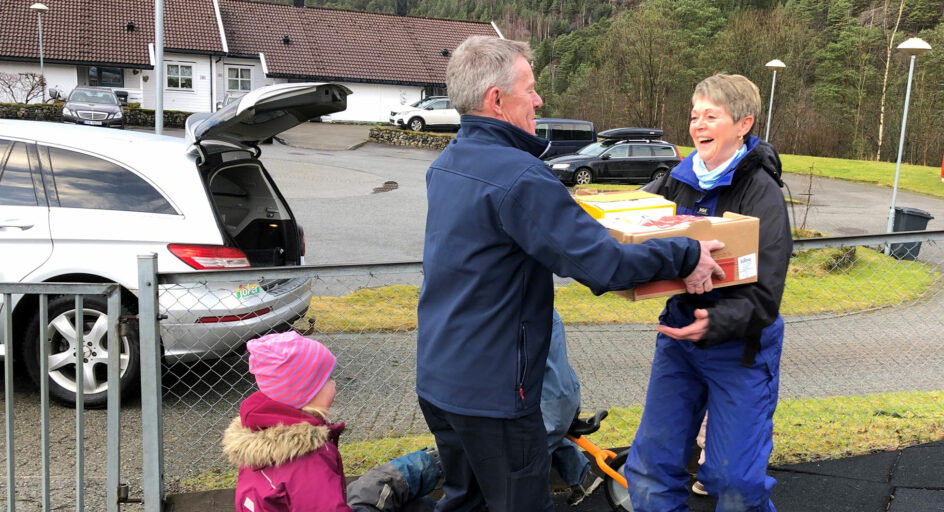 Person leverar ein kasse til ein annan. Foto.