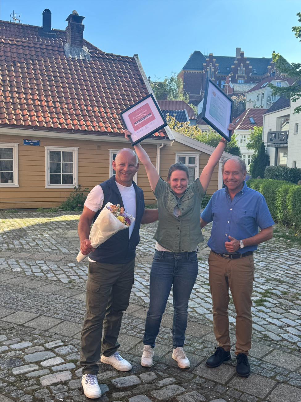 Tre personer med blomster og diplomer