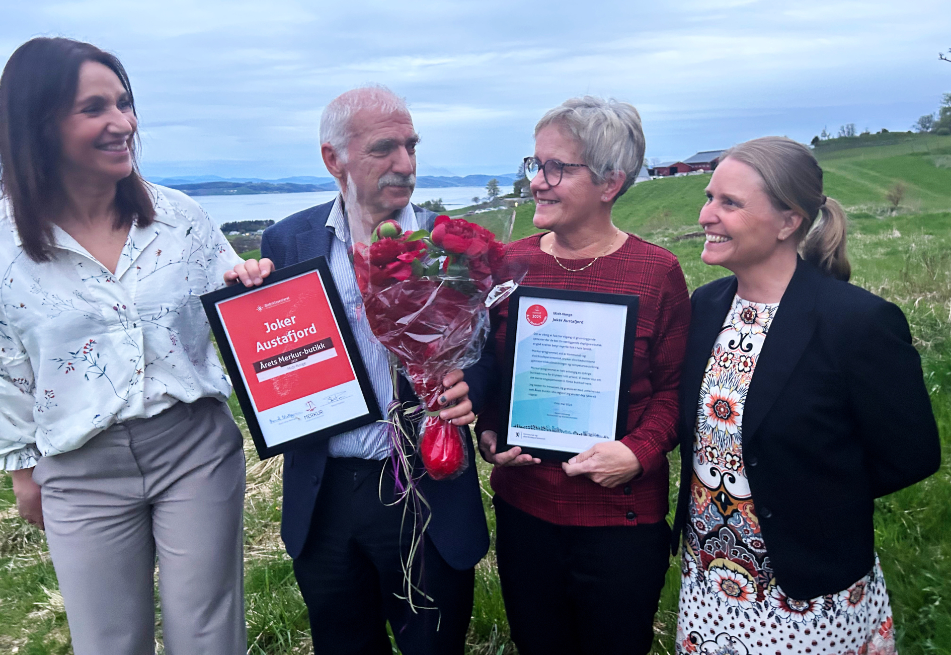 En gruppe mennesker som står ved siden av hverandre og holder blomster og diplomer