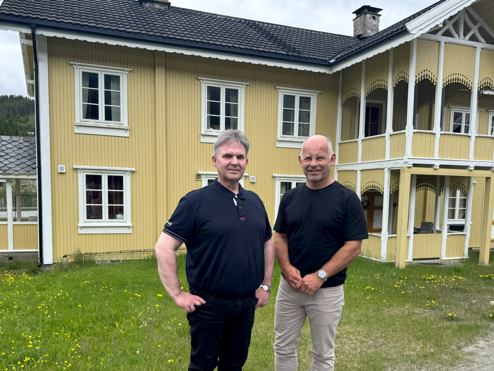 To menn framom eit gamalt, gult hus.