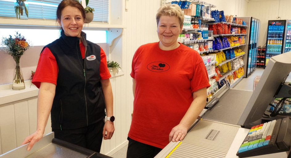 To kvinner som står bak kassen i en dagligvarebutikk