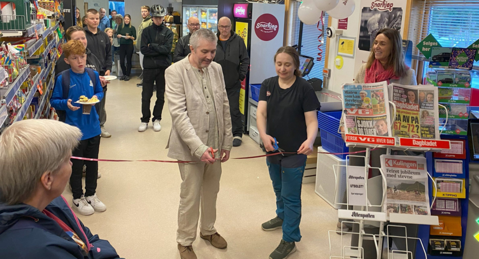En gruppe mennesker som står i en butikk. Klipping av snor.